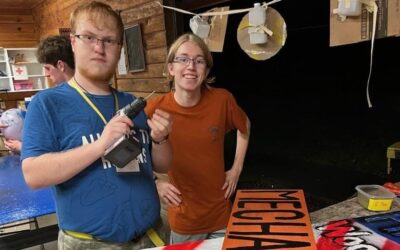 Two male Camp Gorton staffers building wooden signs to prepare for Cub Scout Camp