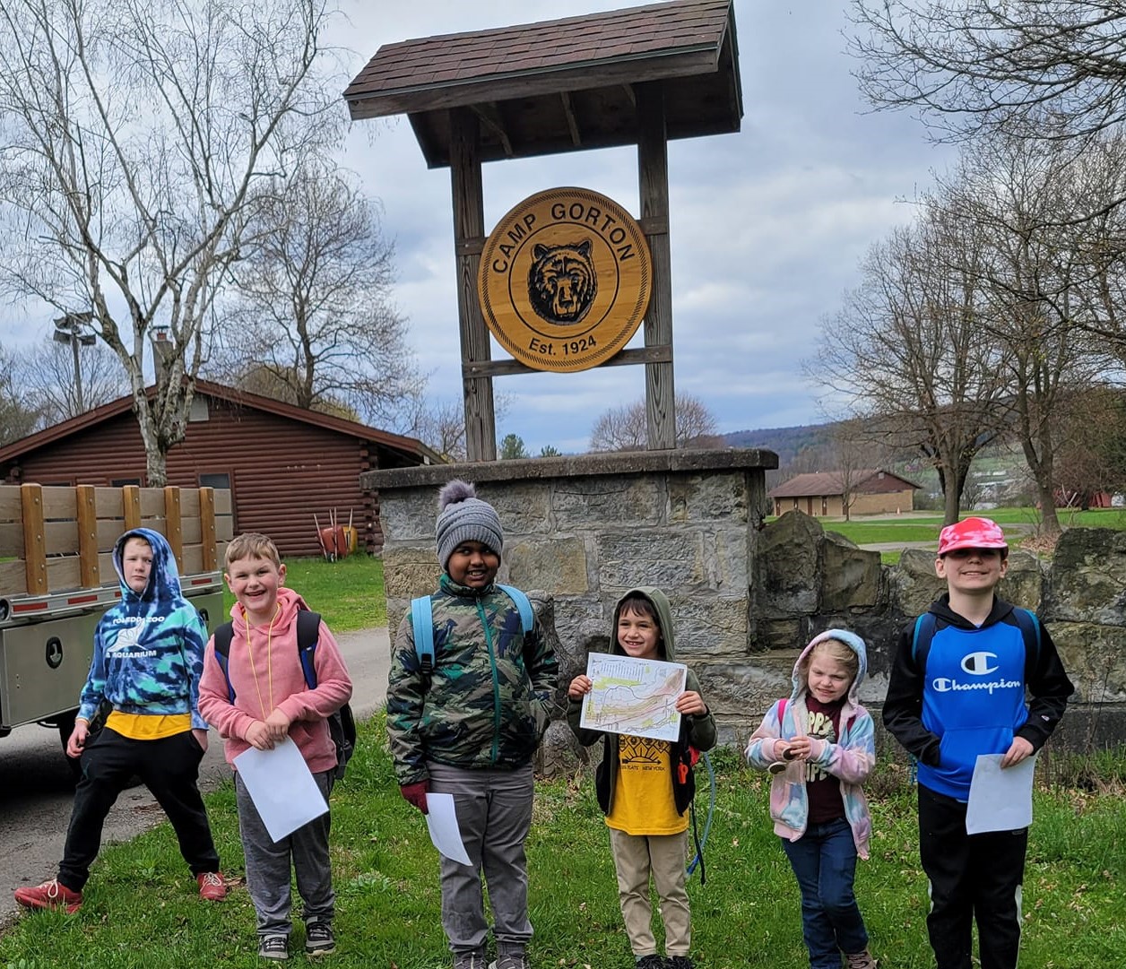 6 Cub Scout boy and girl members with maps in front of the sign for Camp Gorton