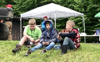 Three male Scouts relax on the grass during a break