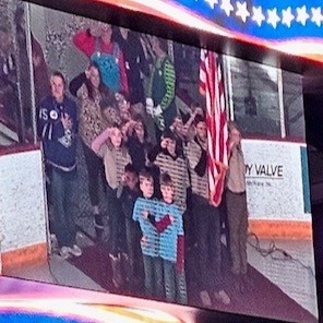 View of the stadium's jumbotron showing the Scouts saluting the American flag